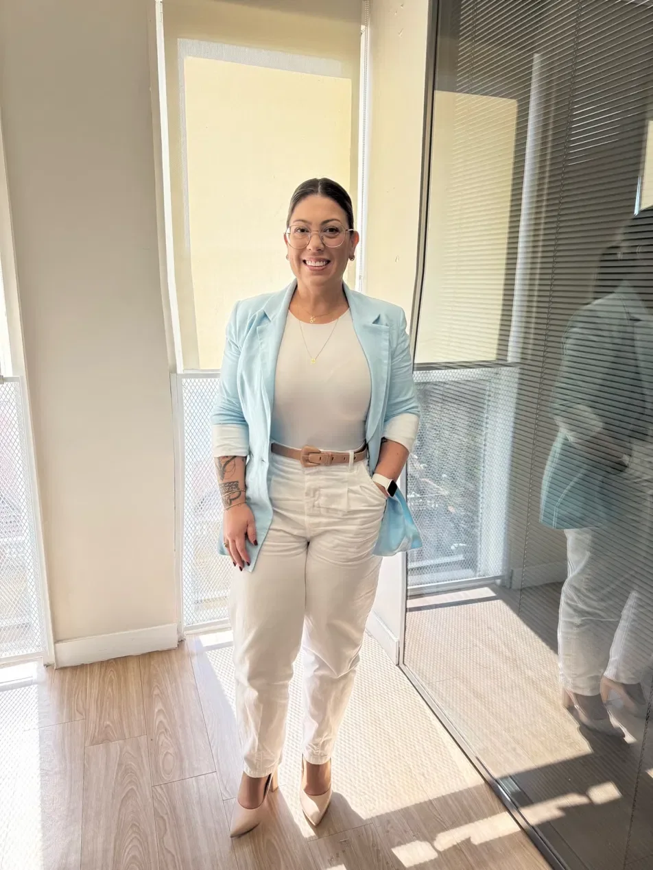 Kelly Guimarães sorrindo em um ambiente iluminado.